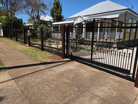 Tubular driveway gate between timber posts